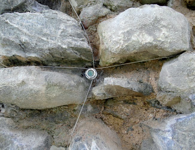 Kotwa stalowa osadzona w murze, widoczne linki stalowe.